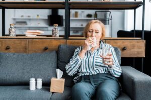 a lady sitting on the couch suffering from flu