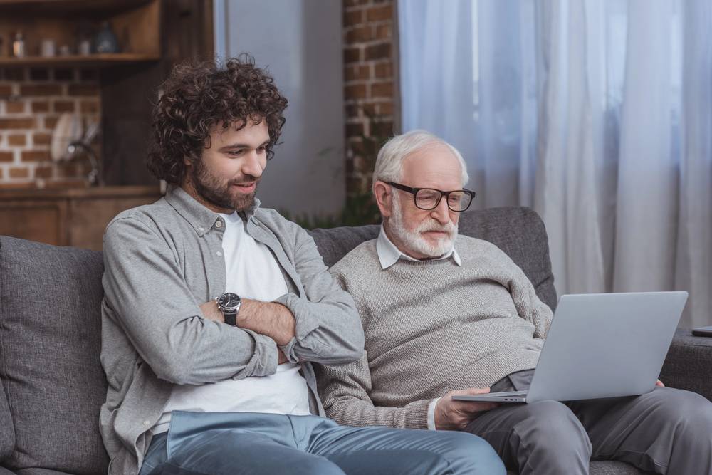 son and dad using laptop together